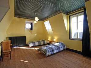 A room with two beds, a radiator, a window, and a ceiling with a patterned design.