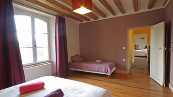 Een slaapkamer met een bed, een raam met gordijnen, een deur en een houten plafond.