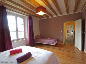 Een slaapkamer met een bed, een raam met gordijnen, een deur en een houten plafond.