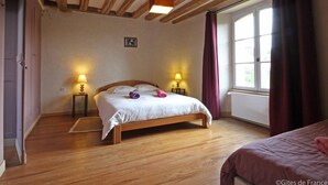 Een slaapkamer met een houten bed, twee bedlampen, een raam met gordijnen en een houten plafond.