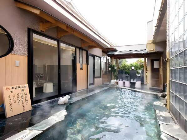 A spa area with a hot spring, wooden benches, and a glass-enclosed room.