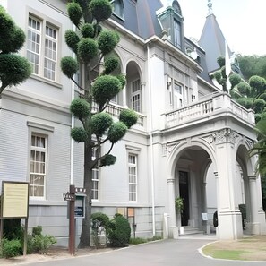 A large, white building with multiple windows and a prominent entrance with an archway. - Business Hotel Taihei Annex (Matsuyama)