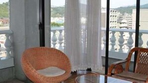 Un balcón con mobiliario de mimbre y una mesa de vidrio, con vistas a la ciudad.