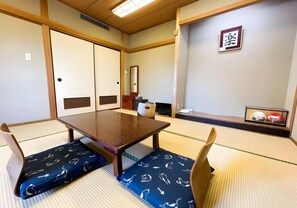 Una habitación tradicional japonesa con suelo de tatami, una mesa de madera baja y dos esteras de tatami con cojines.