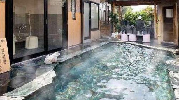 Un bâtiment de style japonais traditionnel doté d’un espace de baignade avec source thermale.