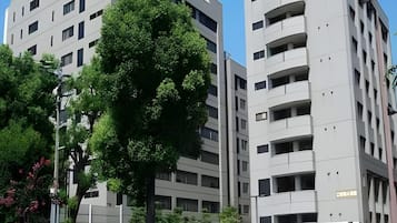 Un bâtiment moderne à plusieurs étages, doté de grandes fenêtres et d’un arbre devant l’entrée.