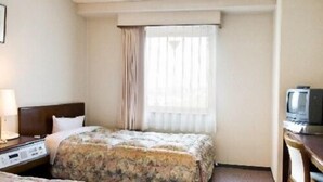 Habitación de hotel con dos camas, un escritorio, una silla, un televisor y una ventana con cortinas.