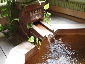 A traditional Japanese water feature with a stone basin and a wooden structure. - Business Hotel Taihei Annex (Matsuyama)