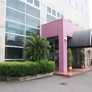 A modern building with a large glass facade and a pink entrance area.