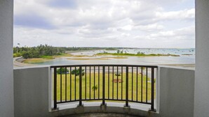 Un balcone con ringhiera nera che si affaccia su uno specchio d'acqua, aree verdi e alberi.