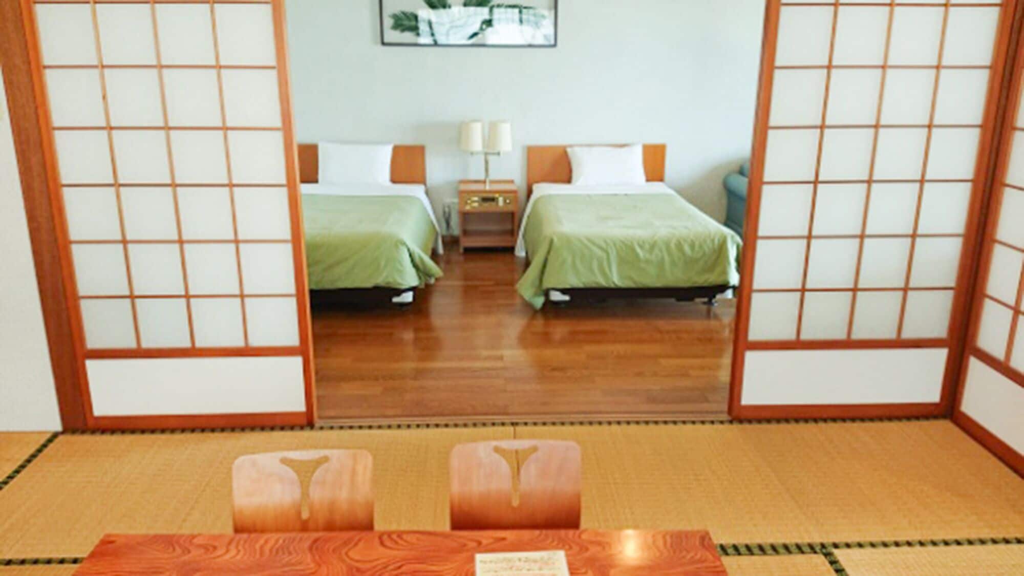 A traditional Japanese-style room with tatami flooring, two beds with green bedding, a nightstand, and a mirror reflecting the room.