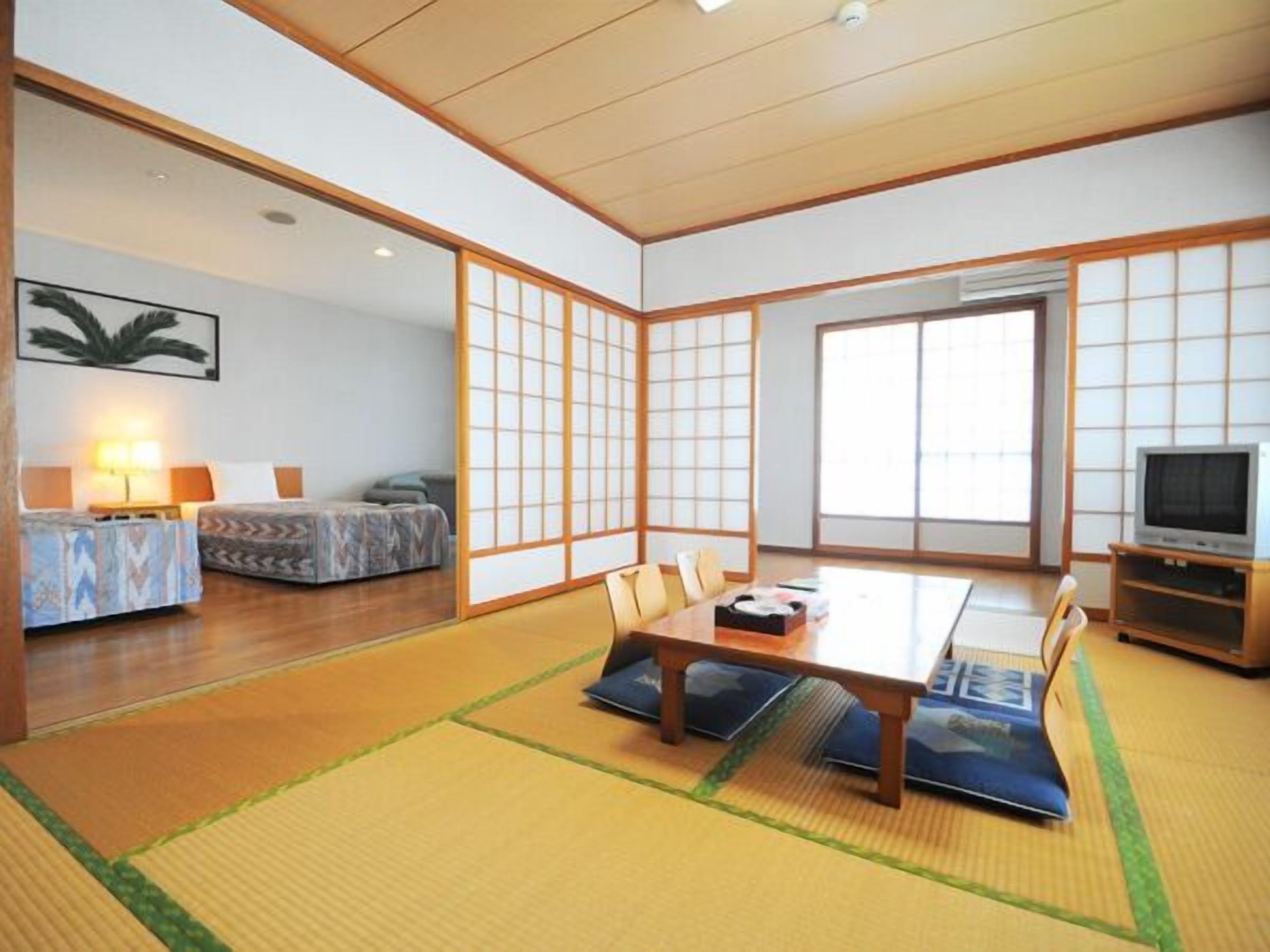 A traditional Japanese room with tatami flooring, a low table, and sliding doors.