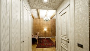 Un pasillo con suelo de madera, puertas blancas, pared de ladrillo y un tapete estampado.