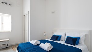 Een hotelkamer met een bed, twee kussens, een nachtkastje, een lamp en een raam.