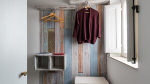 Een badkamer met een rustieke houten wand, een ophangroede, een klein plankje met een boek en een witte bank.