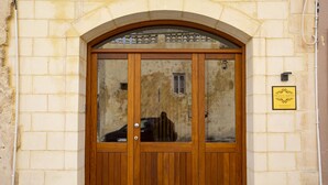 Una porta doble de fusta amb panells de vidre, encaixada en una paret de pedra amb una placa a la part superior.