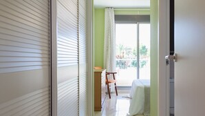Ein Flur mit einer Schiebetür, einem Sessel und einem Bett im Hintergrund.