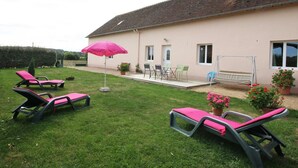 A house with a patio area featuring outdoor furniture, a swing set, and potted plants. - Family stay in the heart of Perche Park (La Chapelle-Souëf)