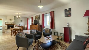 A spacious living room with a fireplace, dining area, and a cozy seating arrangement. - Family stay in the heart of Perche Park (La Chapelle-Souëf)
