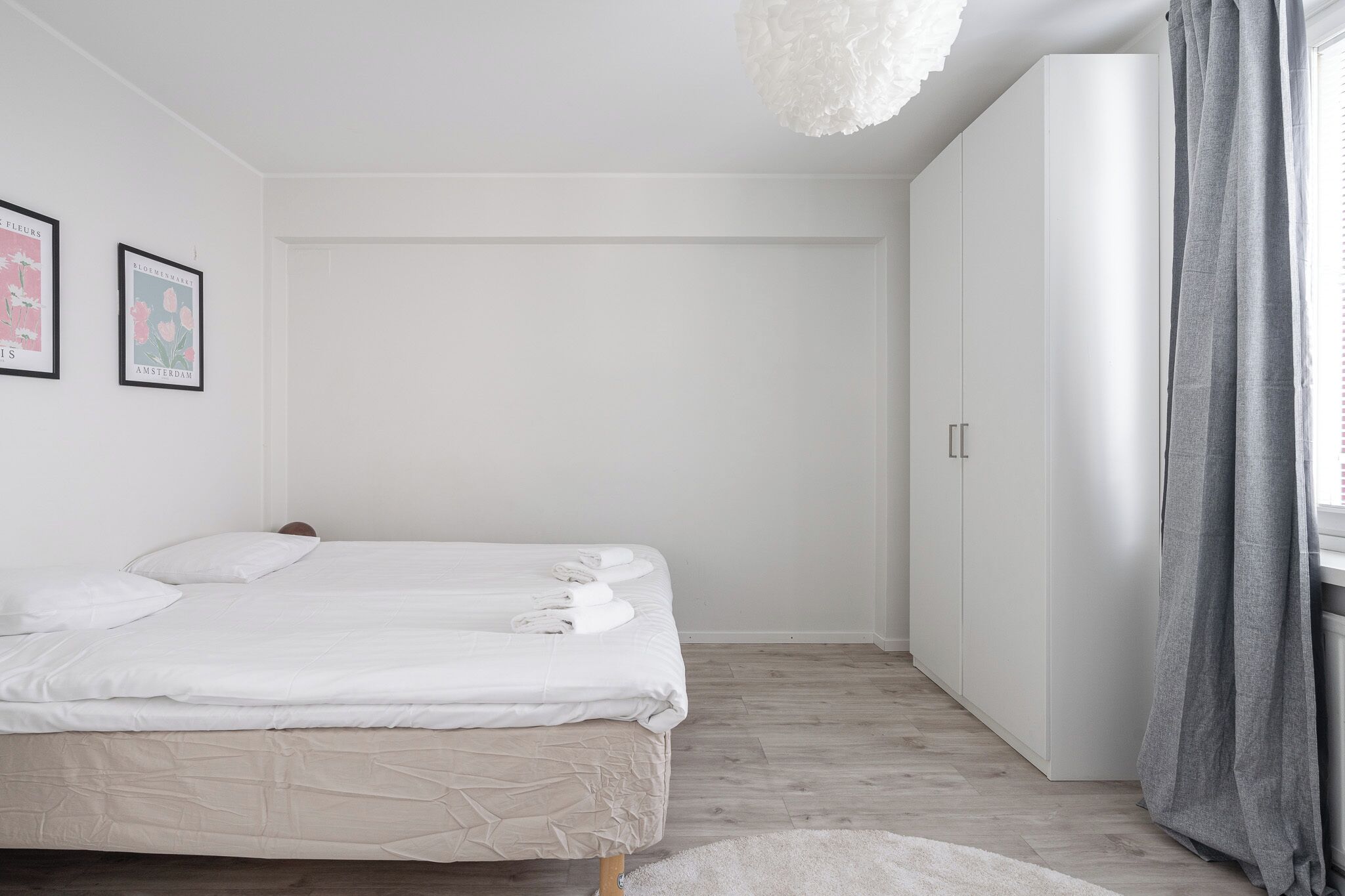 A bedroom with a bed, a wardrobe, and a window with curtains.
