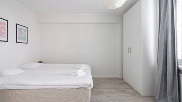 A bedroom with a bed, a wardrobe, and a window with curtains.