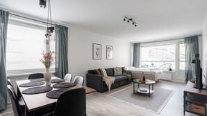 A modern living room with a dining area, a sofa set, and a television. - Spacious Downtown Apt with Balcony that Hosts 10 (Tampere)
