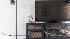 A modern living room with a flat-screen TV, a black floor lamp, a round coffee table, and a decorative vase on a wooden console. - Spacious Downtown Apt with Balcony that Hosts 10 (Tampere)