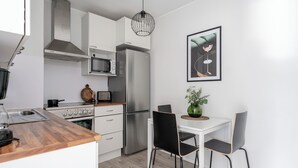 A modern kitchen with white cabinets, stainless steel appliances, and a dining area with a white table and black chairs. - Spacious Downtown Apt with Balcony that Hosts 10 (Tampere)