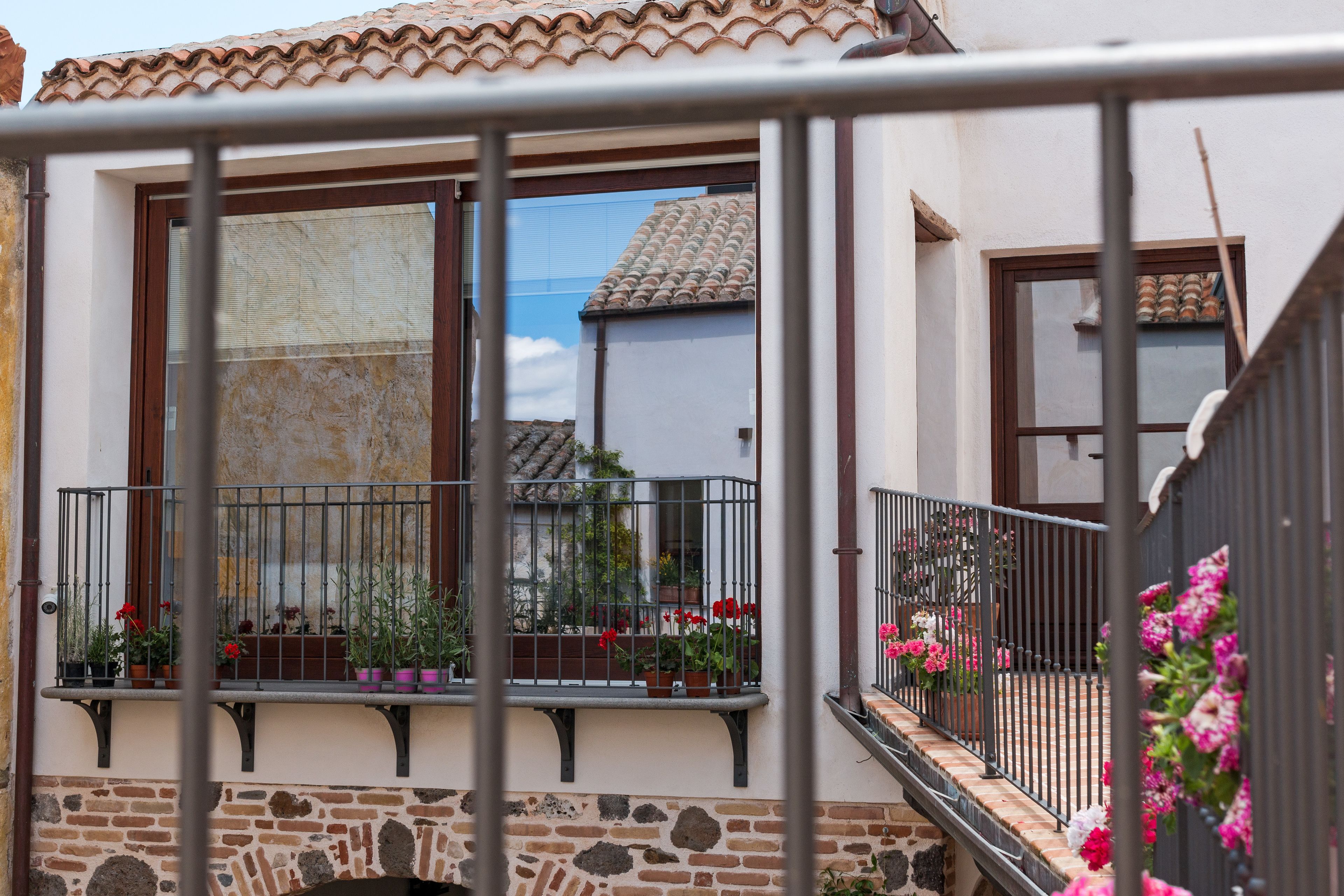 Een balkon met bloembakken en bloemen, een stenen muur en een pannendak.