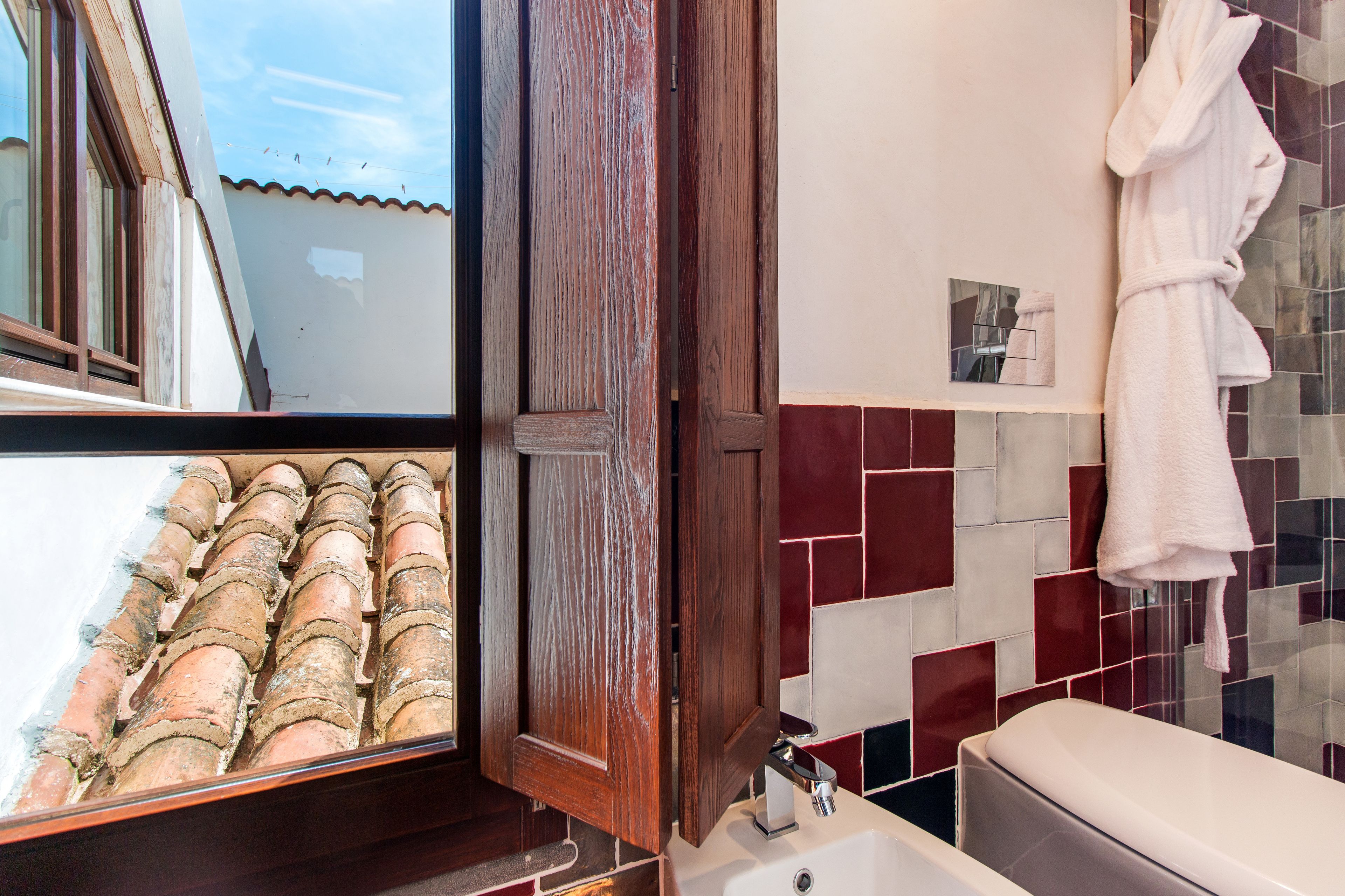 A bathroom with a bathtub, a wooden door, and a tiled wall with a red and white pattern.
