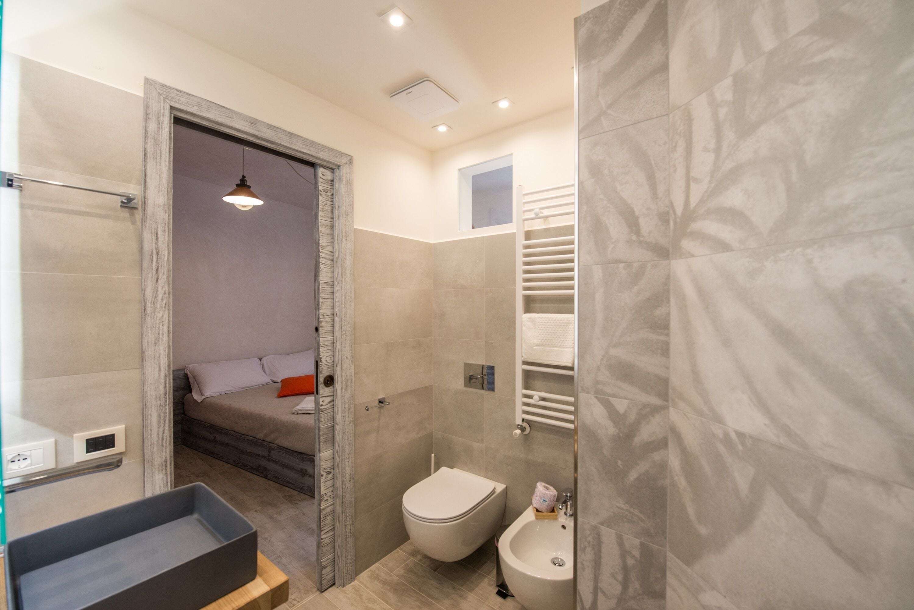 A modern bathroom with a shower, toilet, bidet, and a small sink.