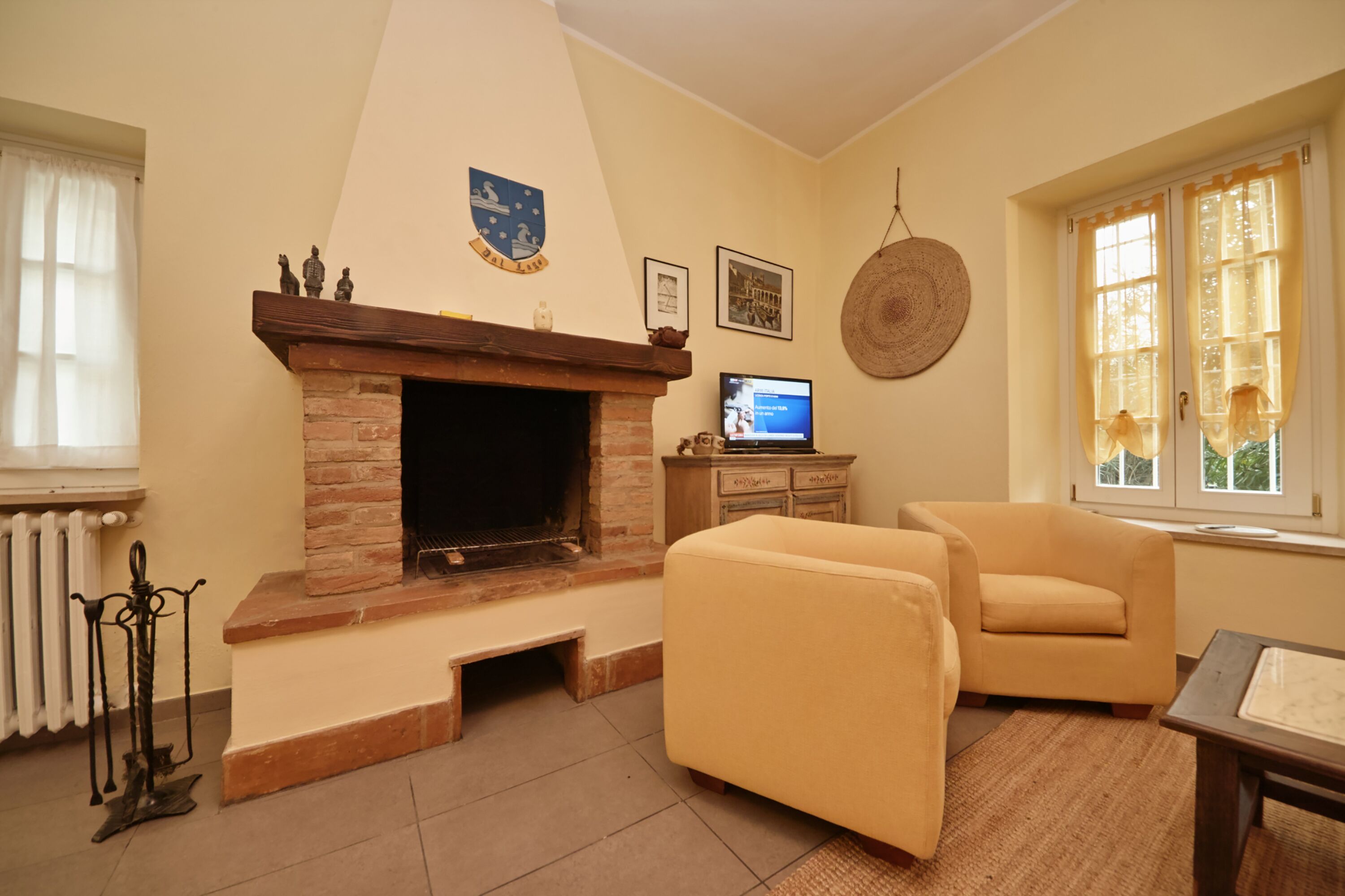 A living room with a fireplace, a television, and two armchairs.