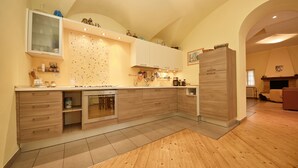A modern kitchen with wooden cabinets, a built-in oven, and a large island. - L'Atelier (Desenzano del Garda)