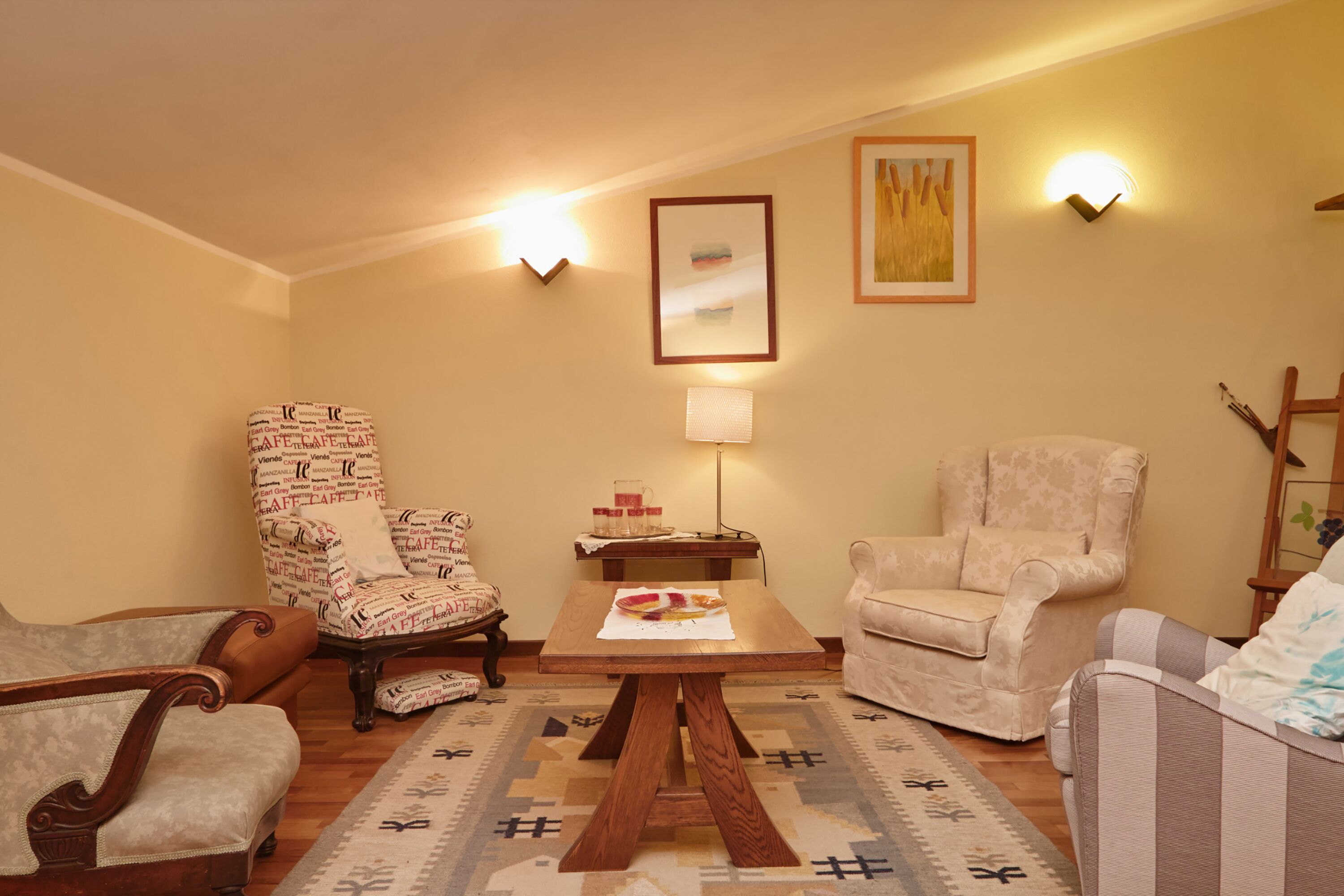 A cozy living room with a wooden coffee table, two patterned armchairs, and a beige sofa.