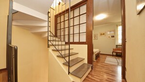 A staircase with wooden steps and metal railings leading to a room with a wooden floor and a window with a view. - L'Atelier (Desenzano del Garda)