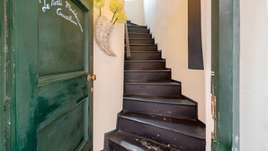 A staircase with a green door labeled "Le Notti Medesette GuestRooms" and a decorative basket with flowers. - Le Notti Mediterranee (Cervo)