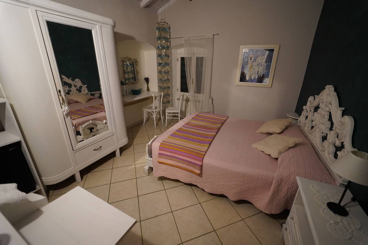 A bedroom with a bed, a wardrobe, a desk, and a chair.