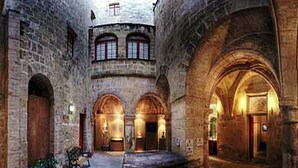 A medieval stone building with arched doorways and a central courtyard. - BOCO Boutique (Cospicua)