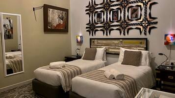 A hotel room with two beds, a large mirror, a decorative wall piece, and a TV.