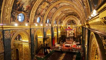 An ornate church interior with a central altar, arched ceilings, and detailed frescoes.
