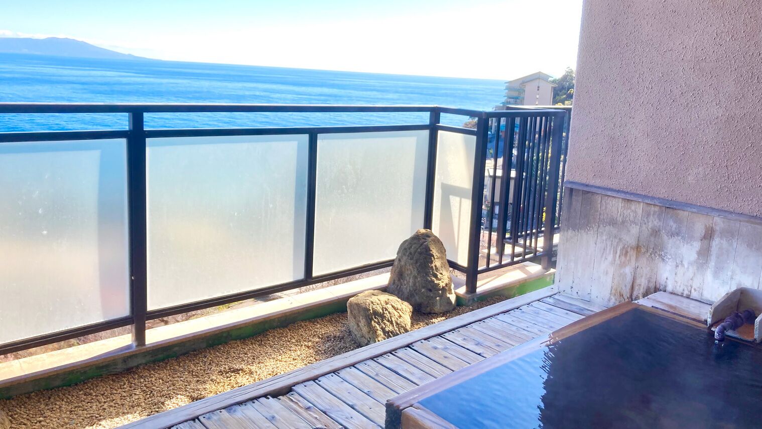 A balcony with a view of the sea, a wooden deck, and a hot tub.
