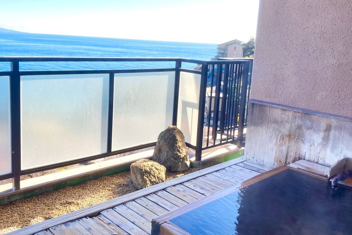 Ein Balkon mit Blick auf das Meer, einer Holzterrasse und einem Whirlpool.