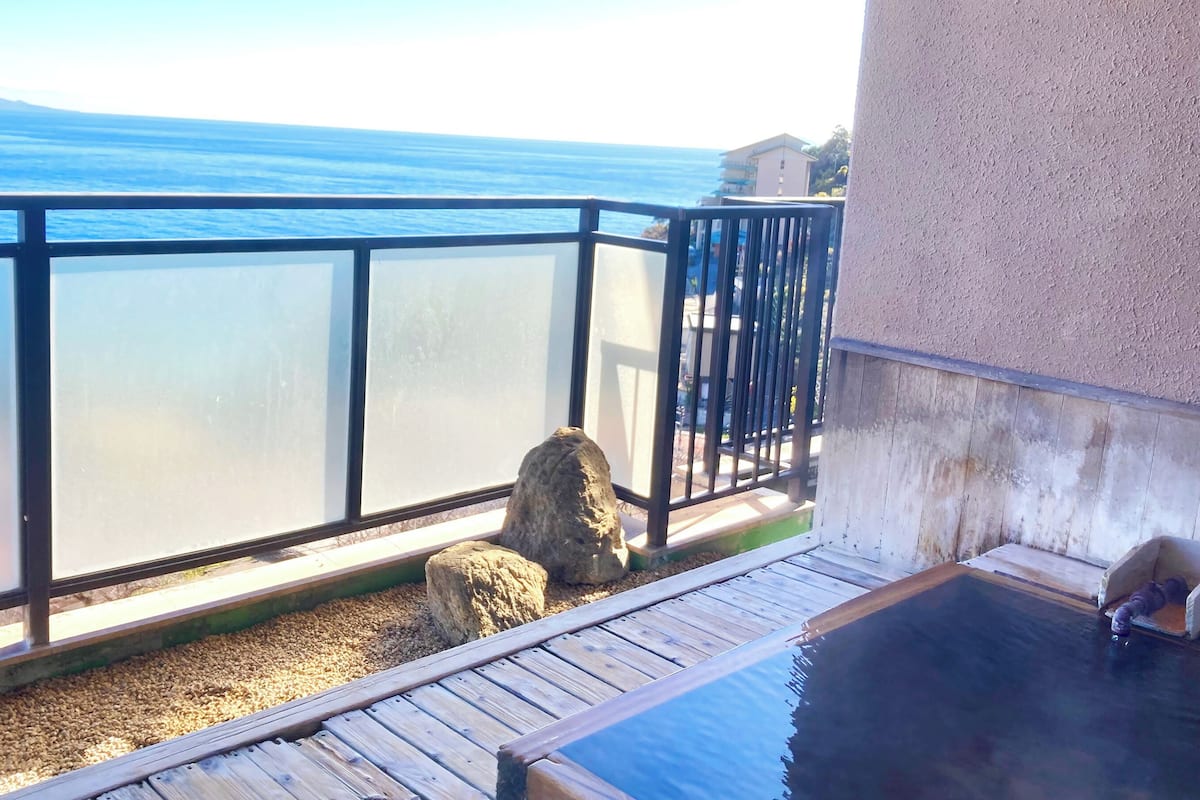 Ein Balkon mit Blick auf das Meer, einer Holzterrasse und einem Whirlpool.