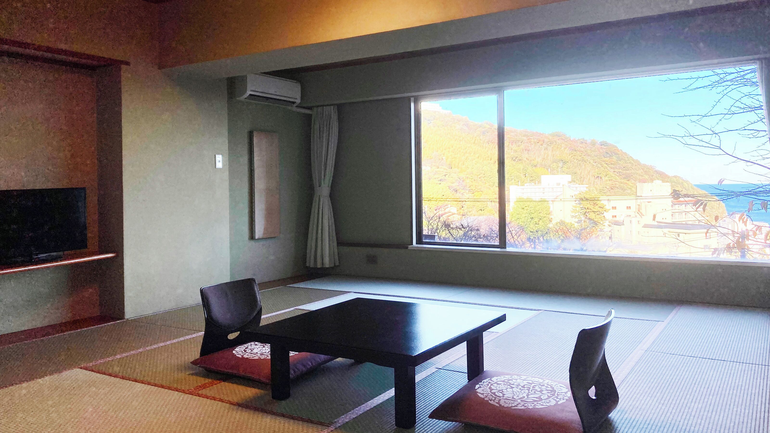 A room with tatami mats, a television, a table, and chairs.
