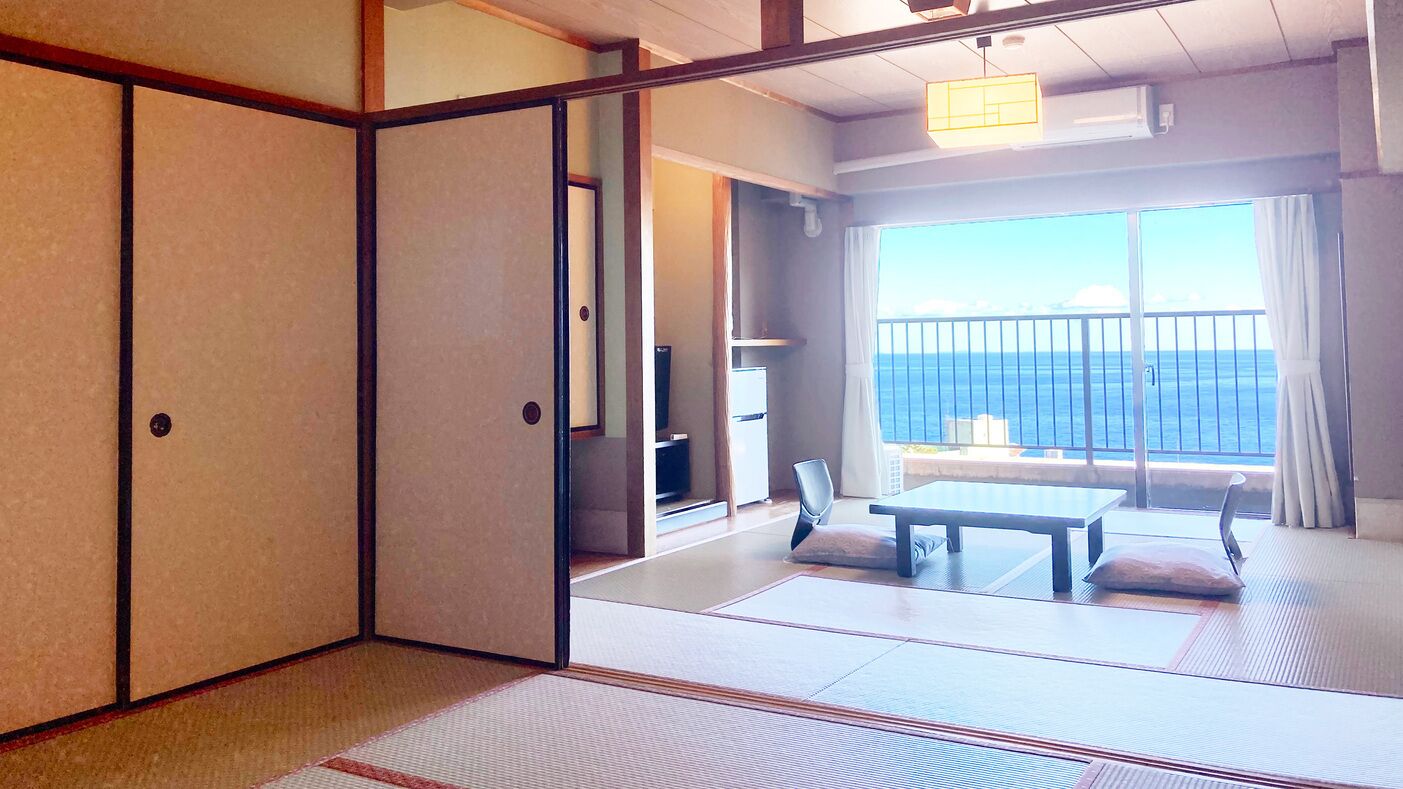 A traditional Japanese room with tatami flooring, a sliding door, a table, and a view of the sea.