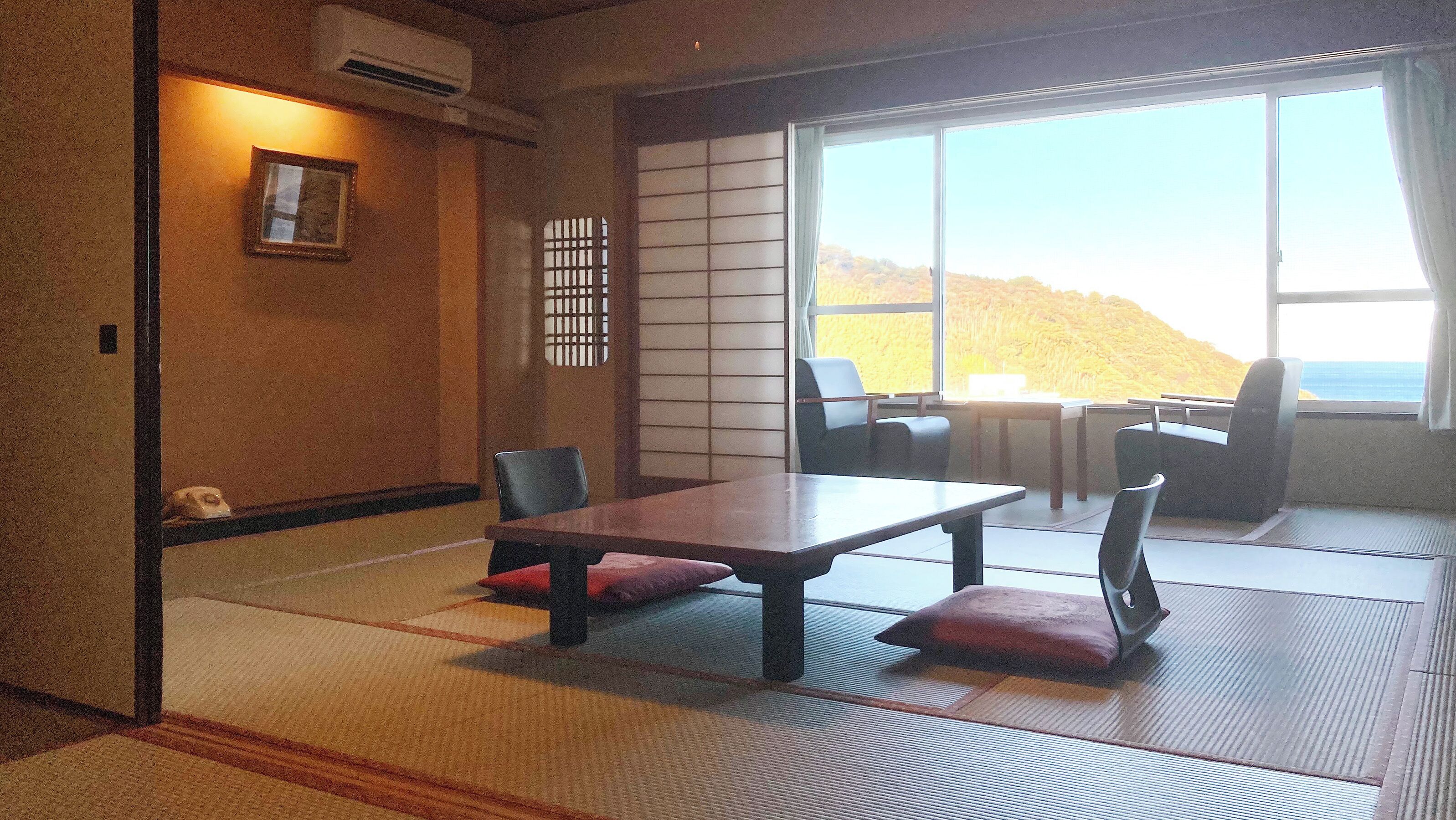 A traditional Japanese room with tatami flooring, a low table with cushions, and a sliding shoji screen.