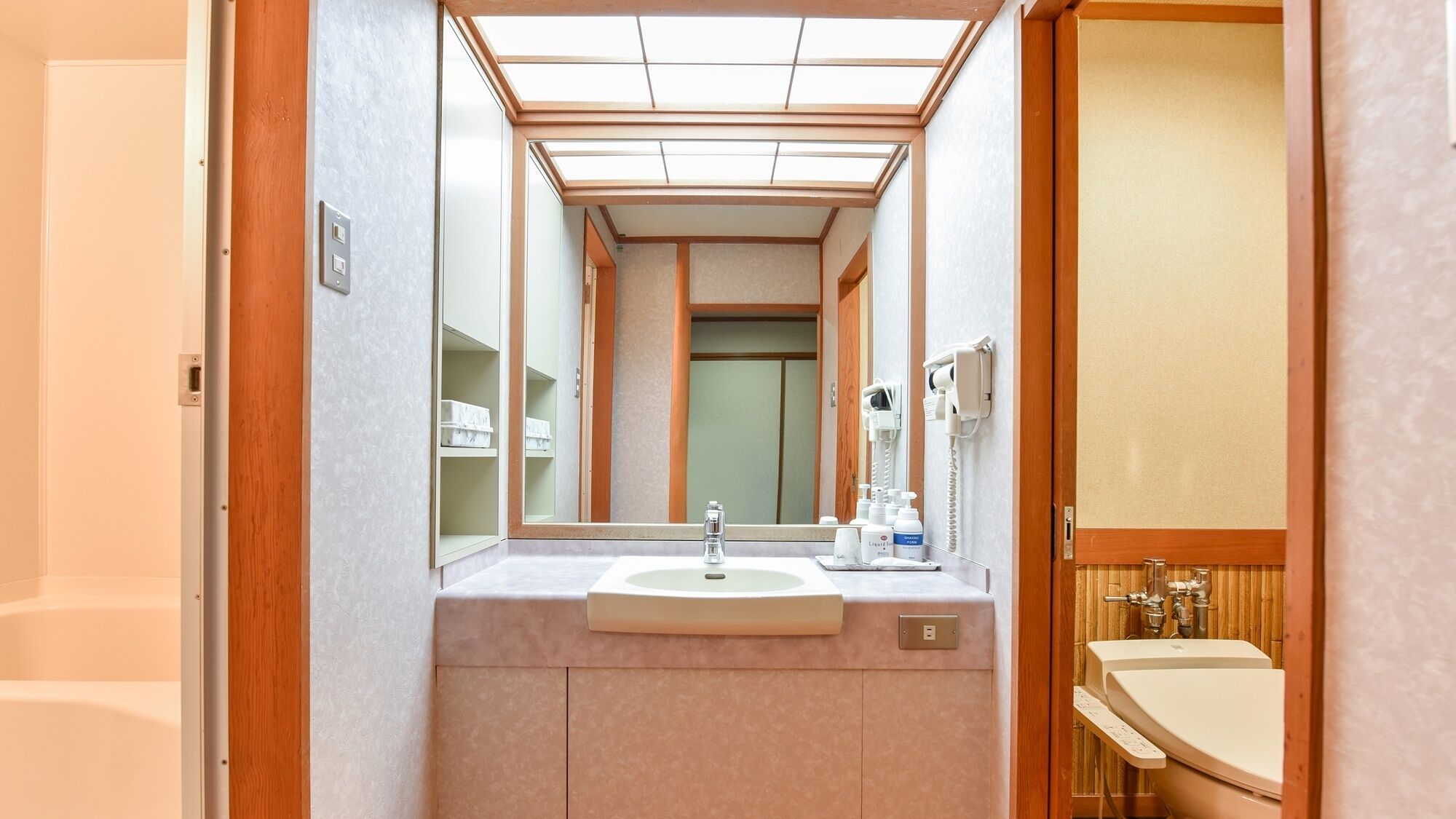 Un baño de hotel estrecho con lavamanos, espejo y teléfono.