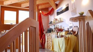 A wooden staircase leading to a room with a tiled floor, a table covered with a yellow cloth, and a shelf with bottles. - Gästehaus und Weingut Peth (Floersheim Dalsheim)