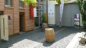 A courtyard with cobblestone pavement, wooden barrels, and hanging plants. - Gästehaus und Weingut Peth (Floersheim Dalsheim)
