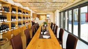 A restaurant with a long wooden table, brown leather chairs, and shelves of wine bottles. - Gästehaus und Weingut Peth (Floersheim Dalsheim)